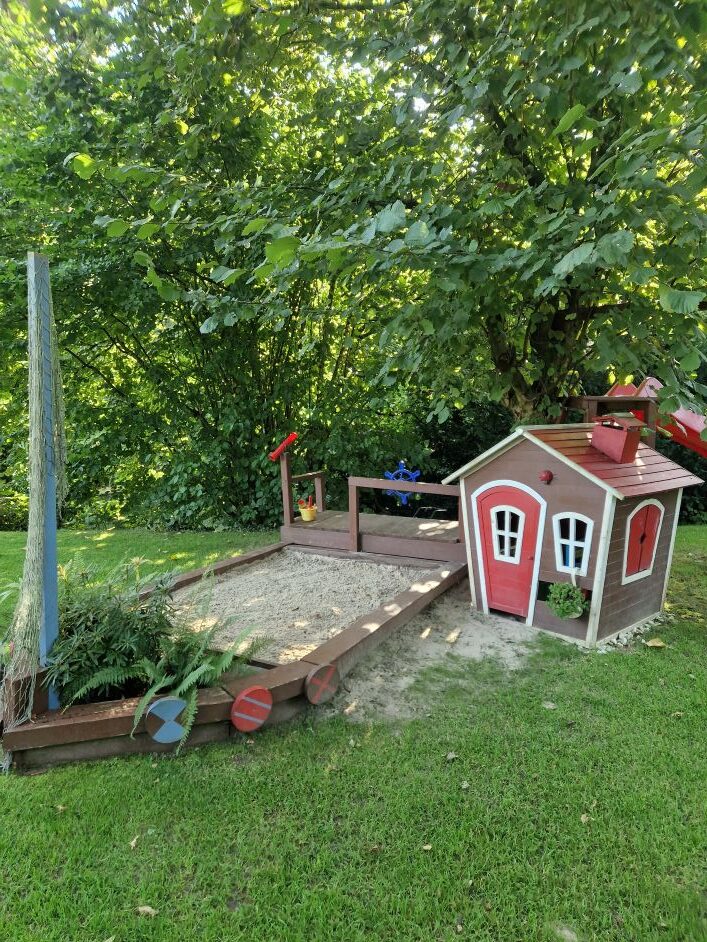Bunte blühende Pflanzen in lila und grün zwischen grauen Steinplatten im Garten.