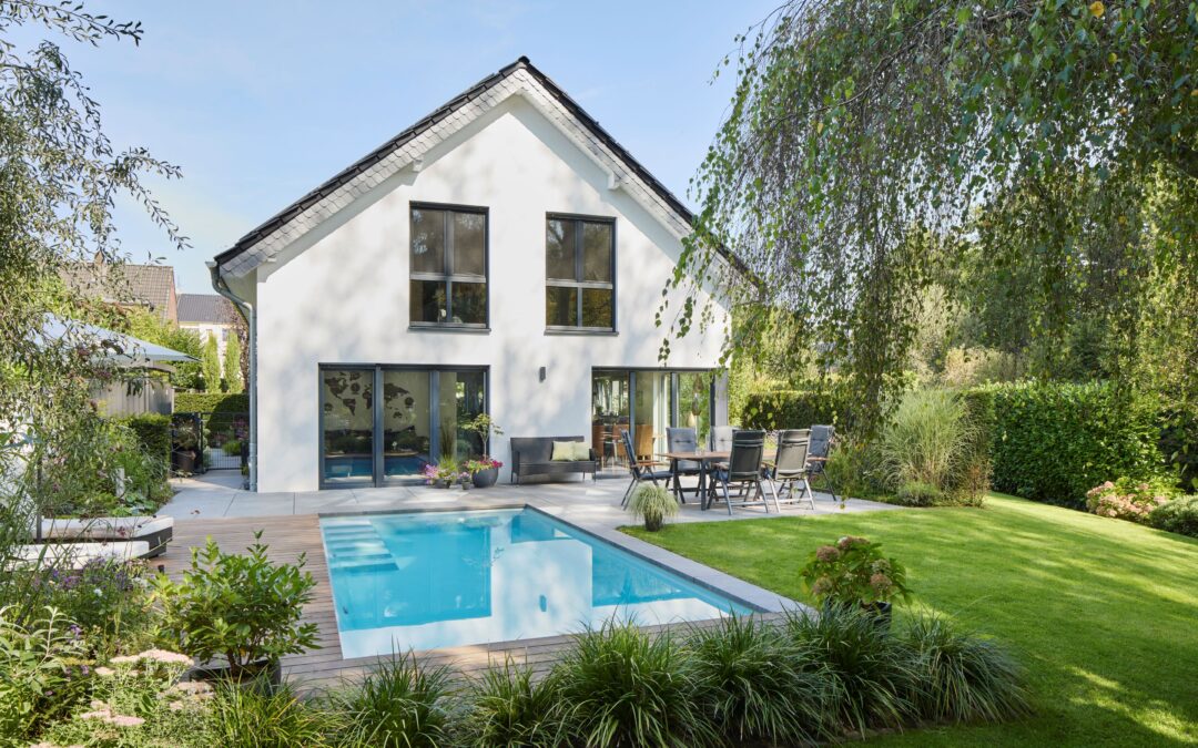 Ein moderner Familiengarten mit rechteckigem Pool, Terrasse und gepflegter Rasenfläche zeigt individuelle Gartengestaltung am Niederrhein.
