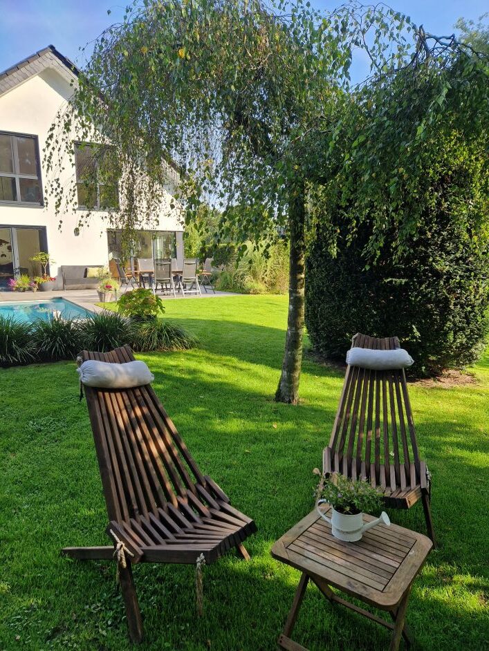 Innenansicht einer Sauna mit Holzbank und Blick auf einen Garten durch ein großes Fenster.