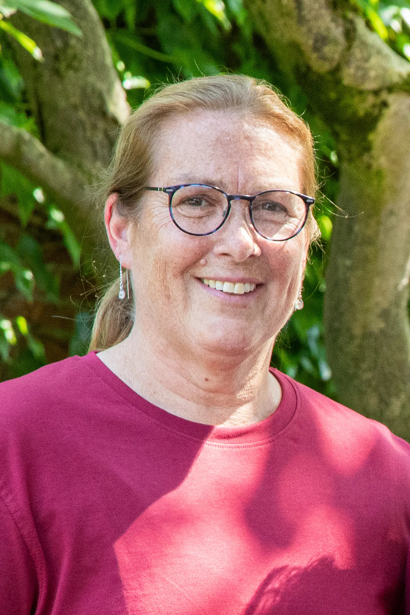 Eine Person mit Brille und grünem T-Shirt sitzt vor einer Backsteinwand.