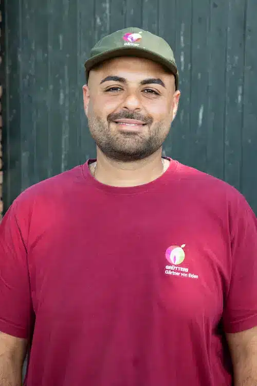 Mann mit Bart und kurzem Haar, trägt ein grünes T-Shirt und lächelt in die Kamera.