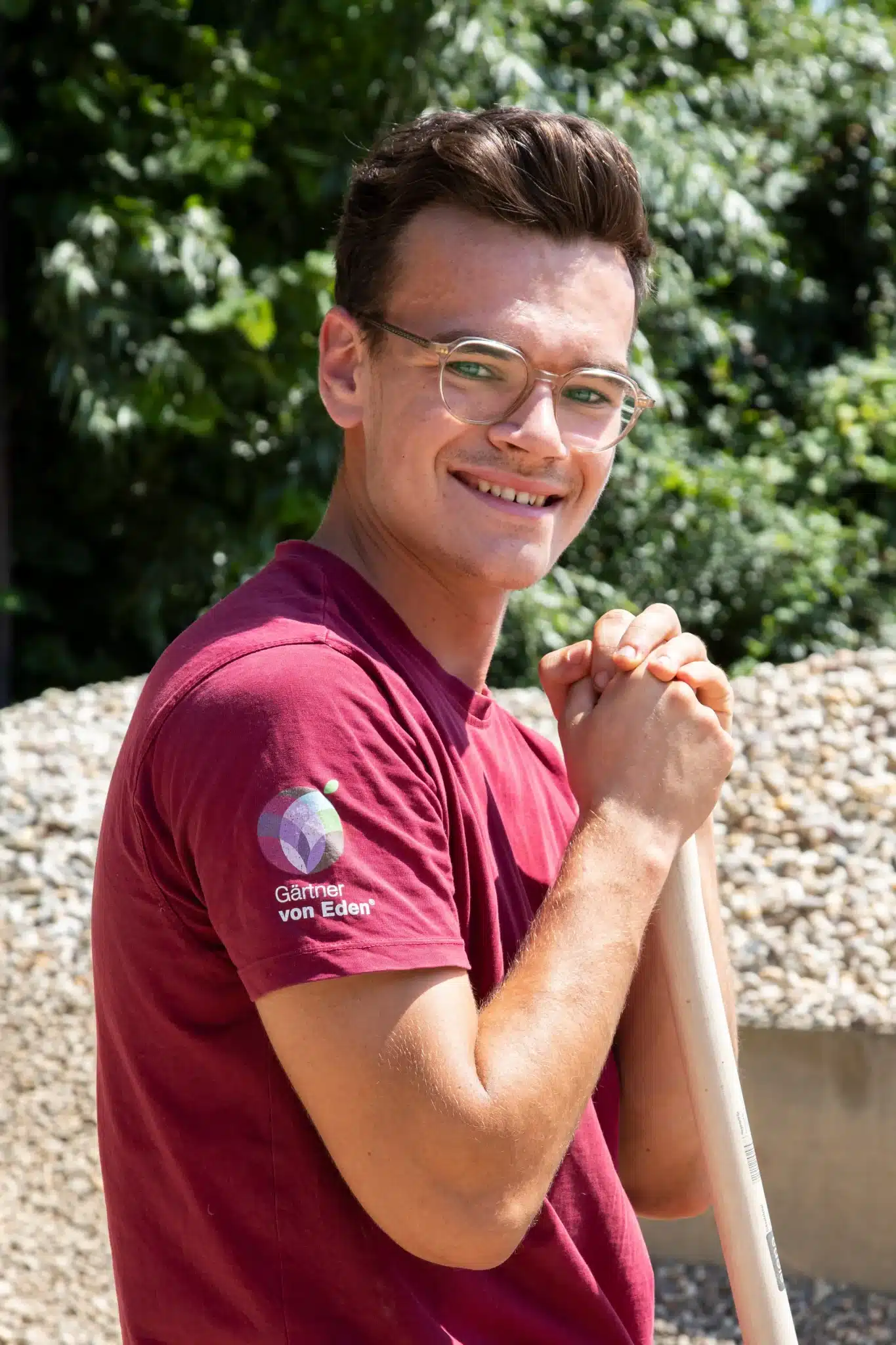 Junger Mann mit lockigem Haar und rotem T-Shirt, der in die Kamera lächelt.
