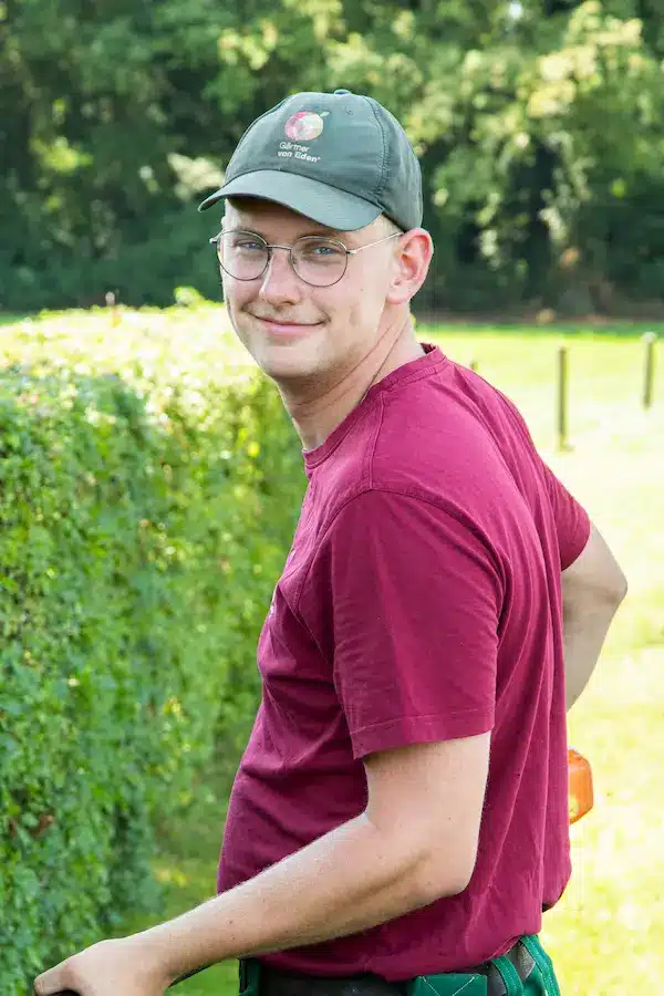 Junger Mann mit blonden Haaren und Brille, der in die Kamera schaut.