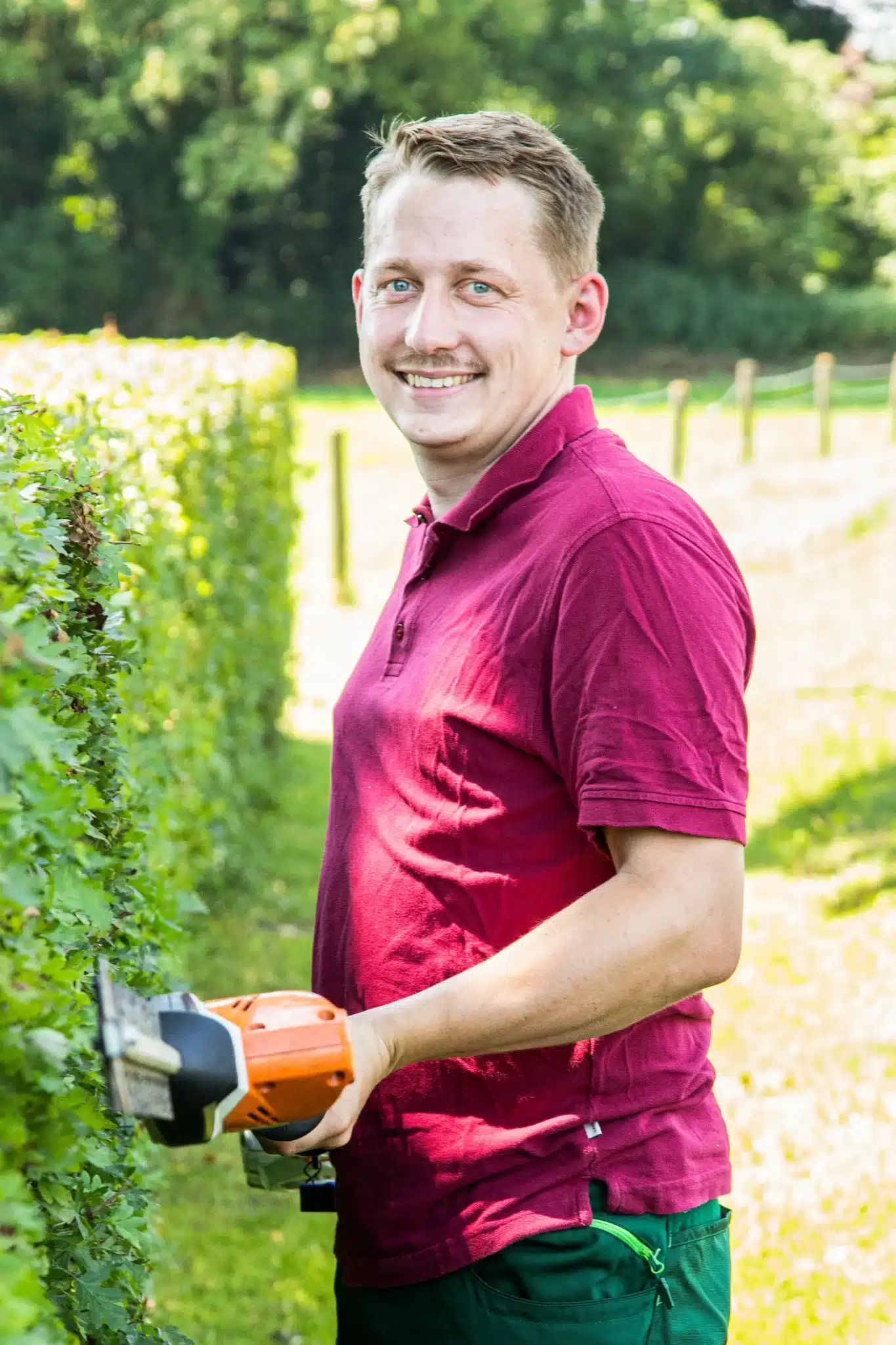 Junger Mann mit grüner Kappe und rotem Poloshirt steht vor einer Felswand.