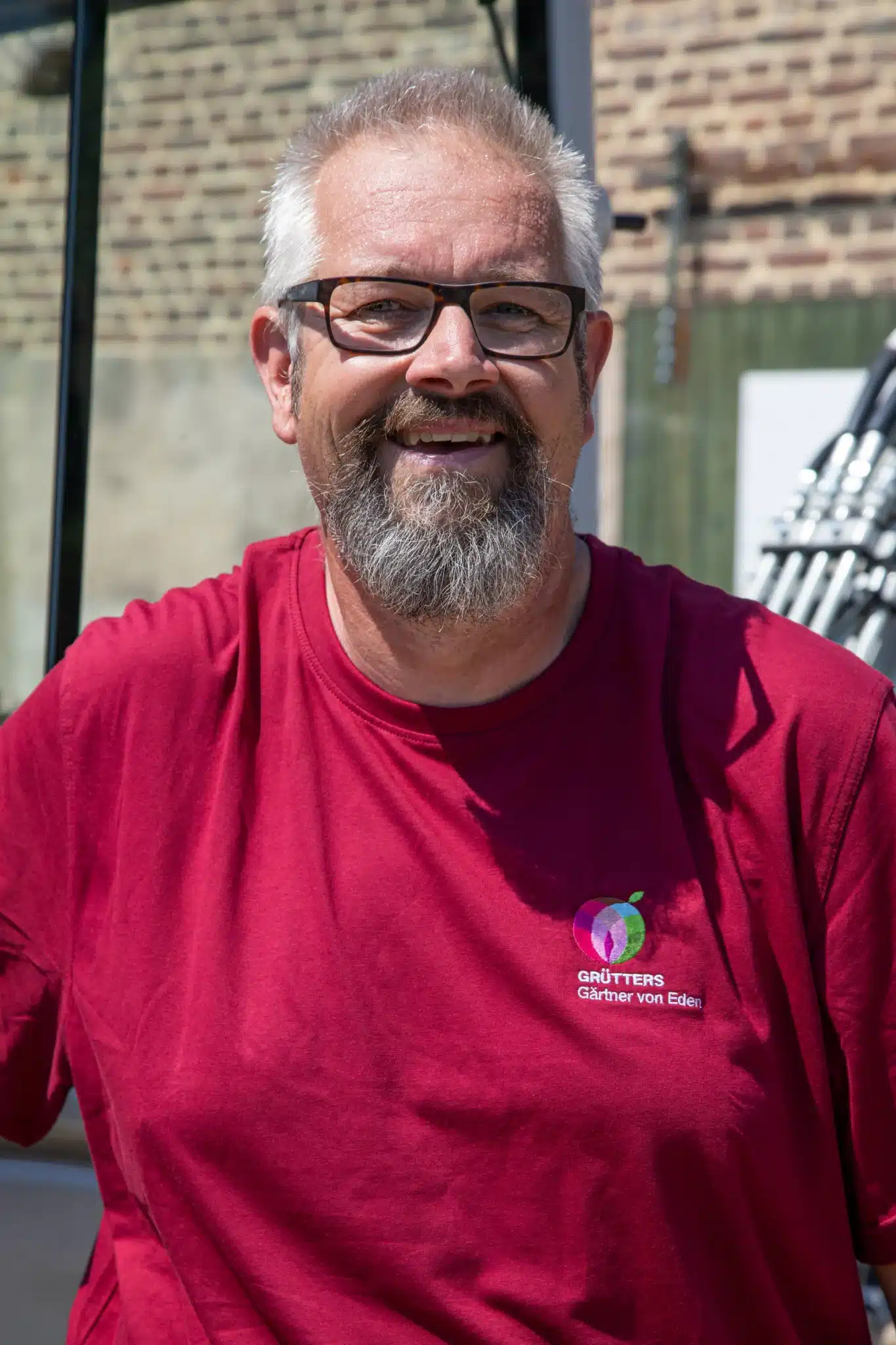 Mann mit Brille, Bart und rotem T-Shirt, lächelt in die Kamera.