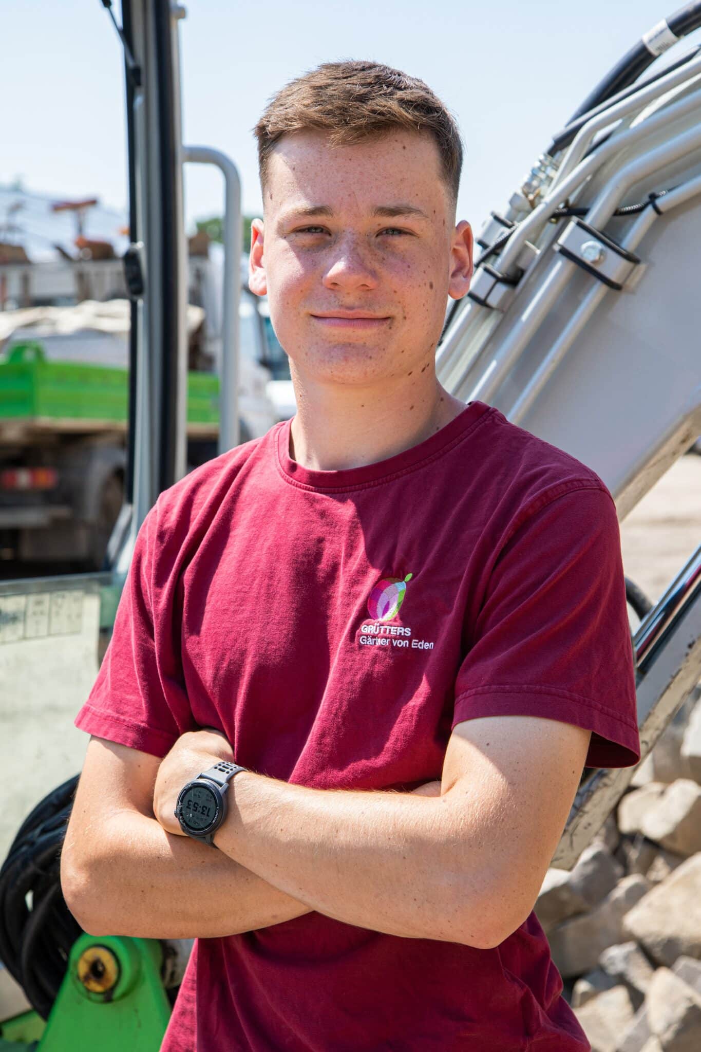Nick Becker Junge in rotem Hoodie steht vor einer rustikalen Holzwand mit sichtbaren Texturen.