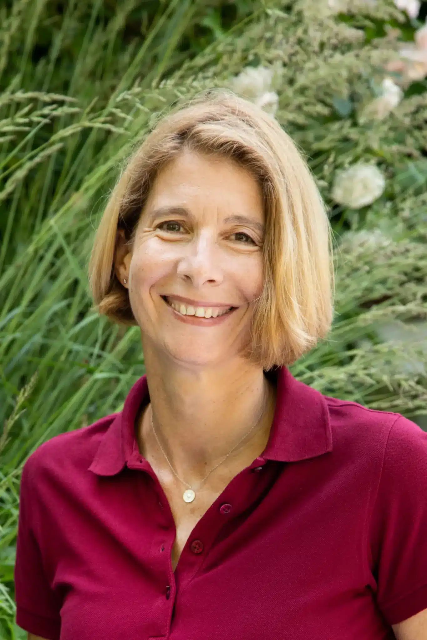 Porträt von Tanja Gaertner mit kurzen braunen Haaren in einem roten Poloshirt.